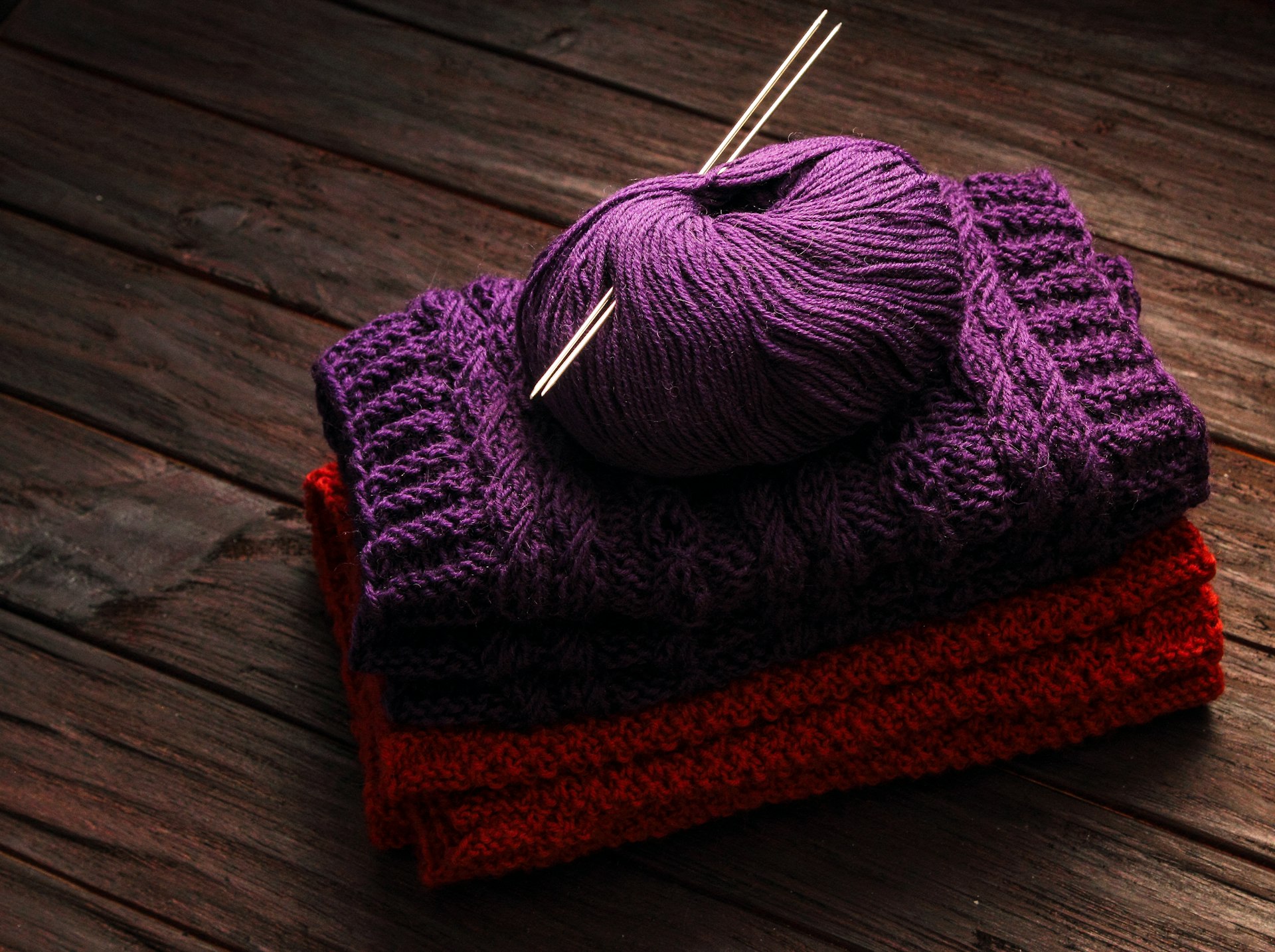 a pile of purple and red yarn sitting on top of a wooden table